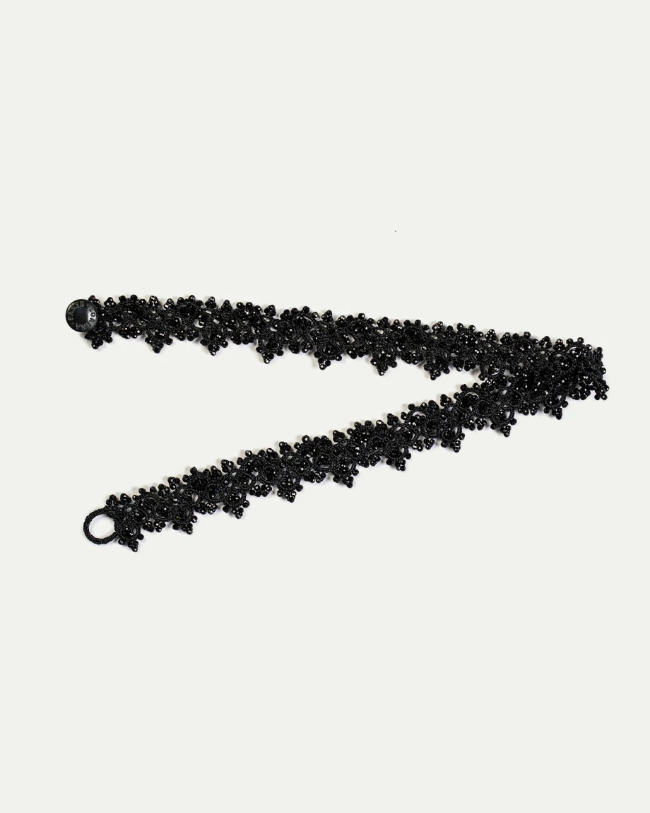 Black silk choker with intricate beaded pearl detailing and clasp, showcasing elegant texture and craftsmanship.