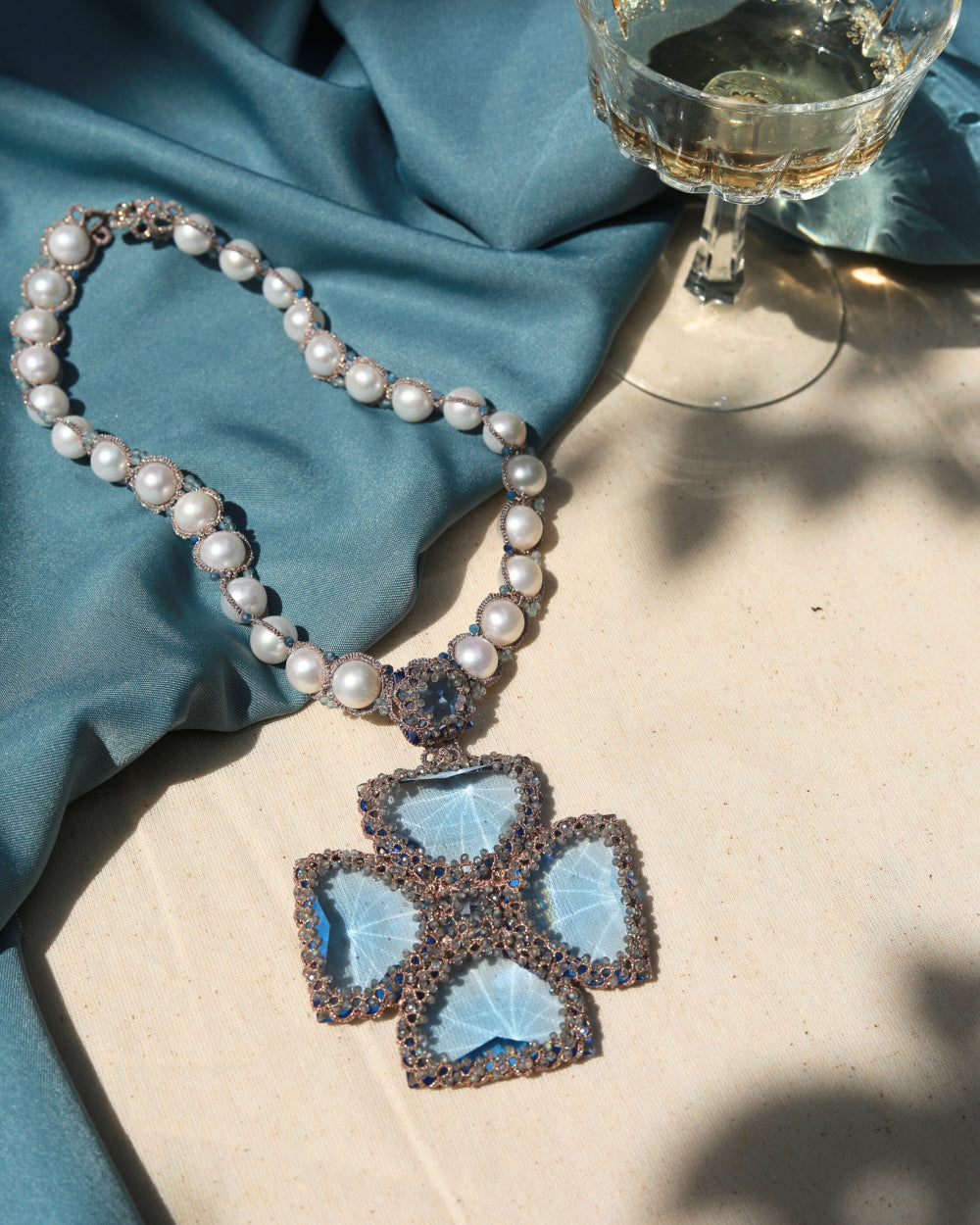 CASSIOPEIA NECKLACE with blue gemstones, freshwater pearls, crystal, and silk background.