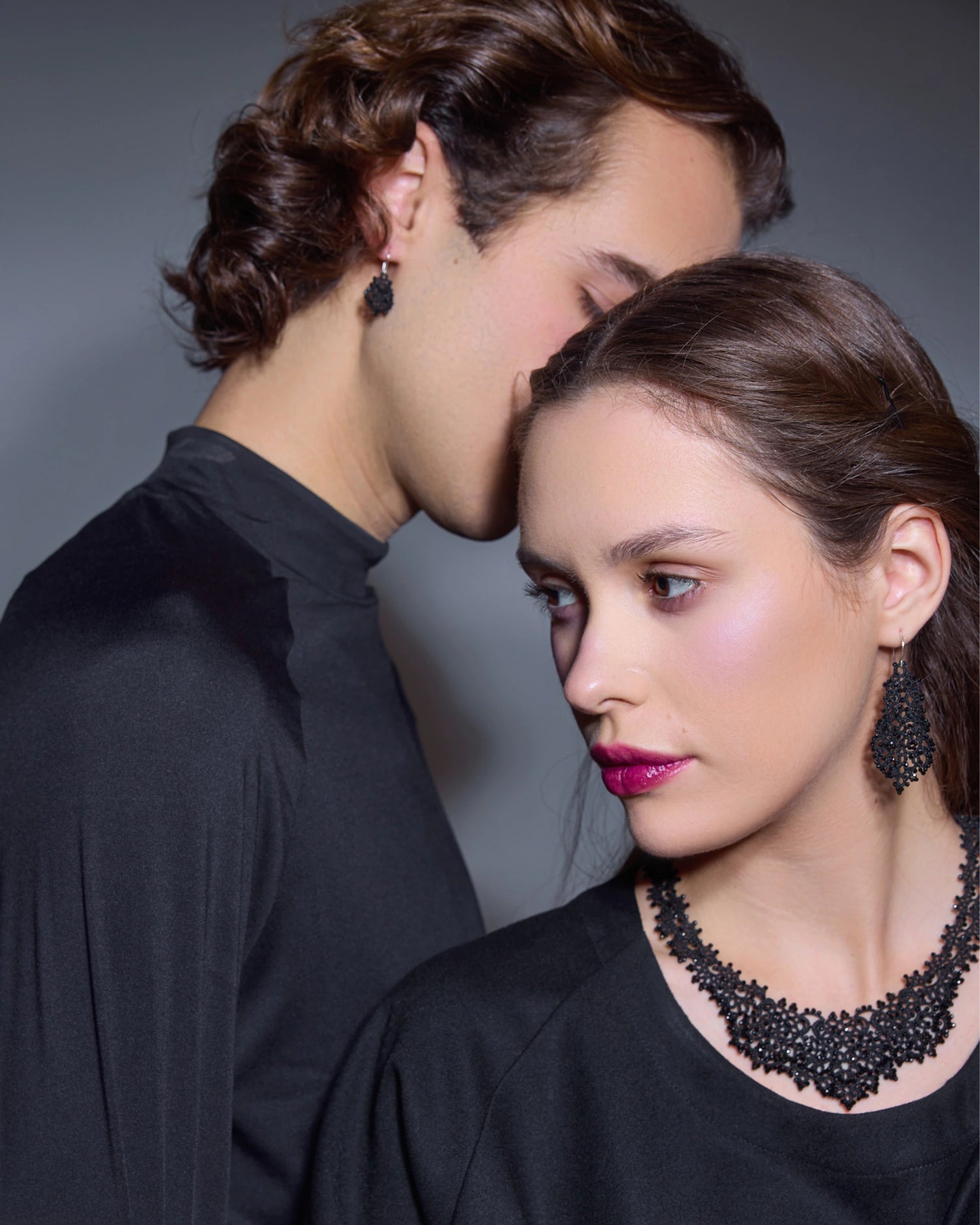 Black silk and silver Dora earrings with intricate detailing, worn by a woman in a styled studio setting.