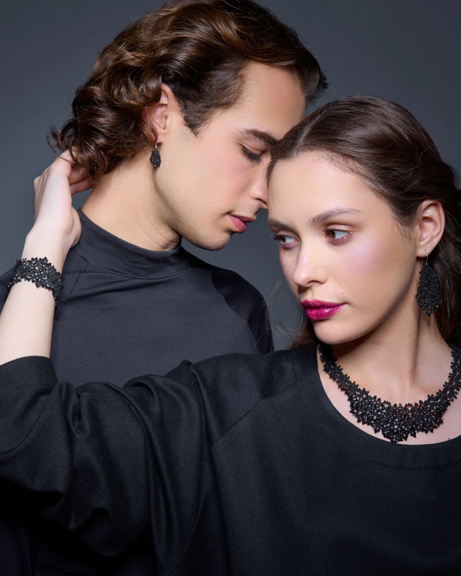 Black silk and silver Dora earrings with intricate texture, worn with matching necklace and bracelet, close-up view.
