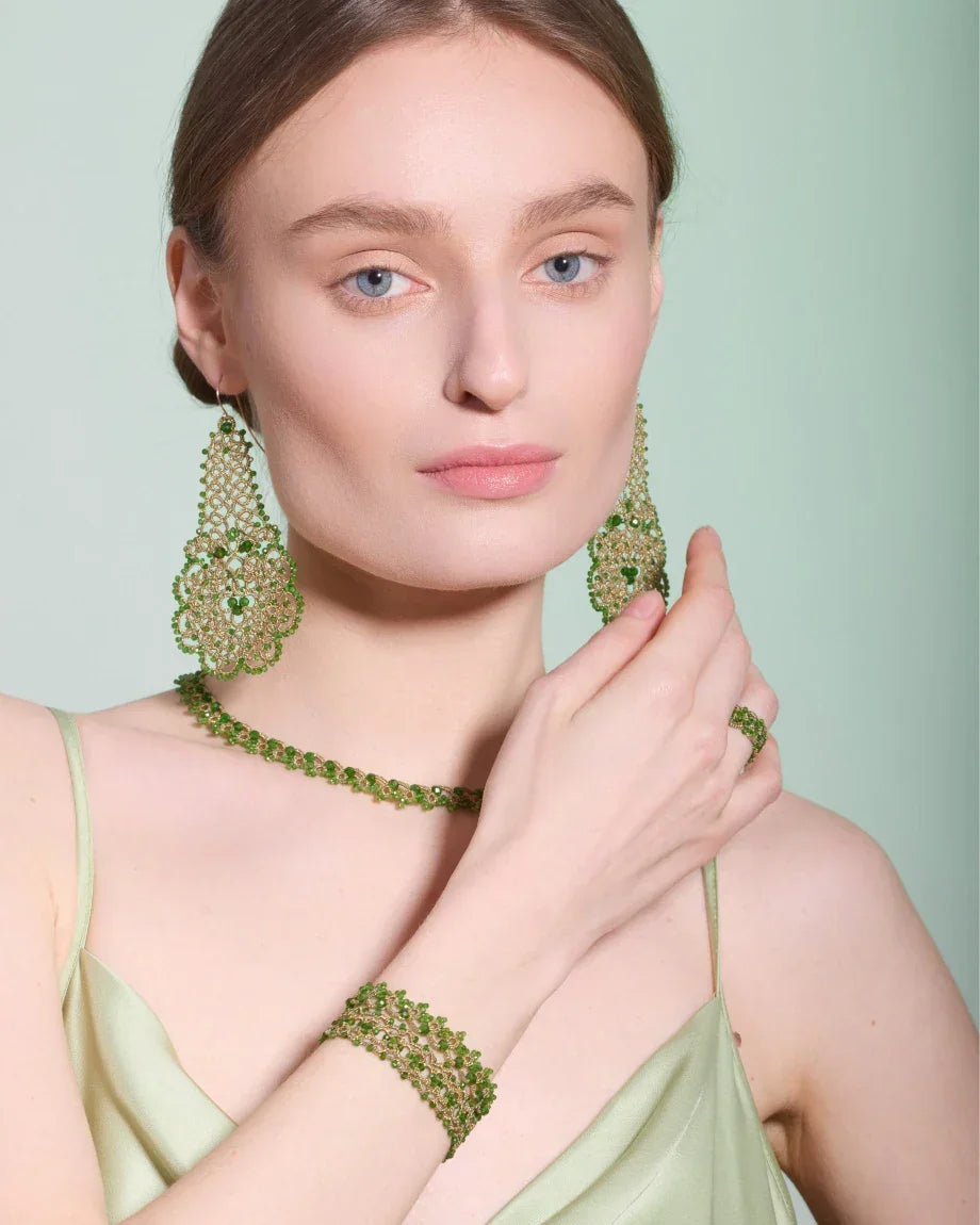 Green Gerbera earrings with intricate beadwork and floral design, shown from side angle, worn with matching necklace.