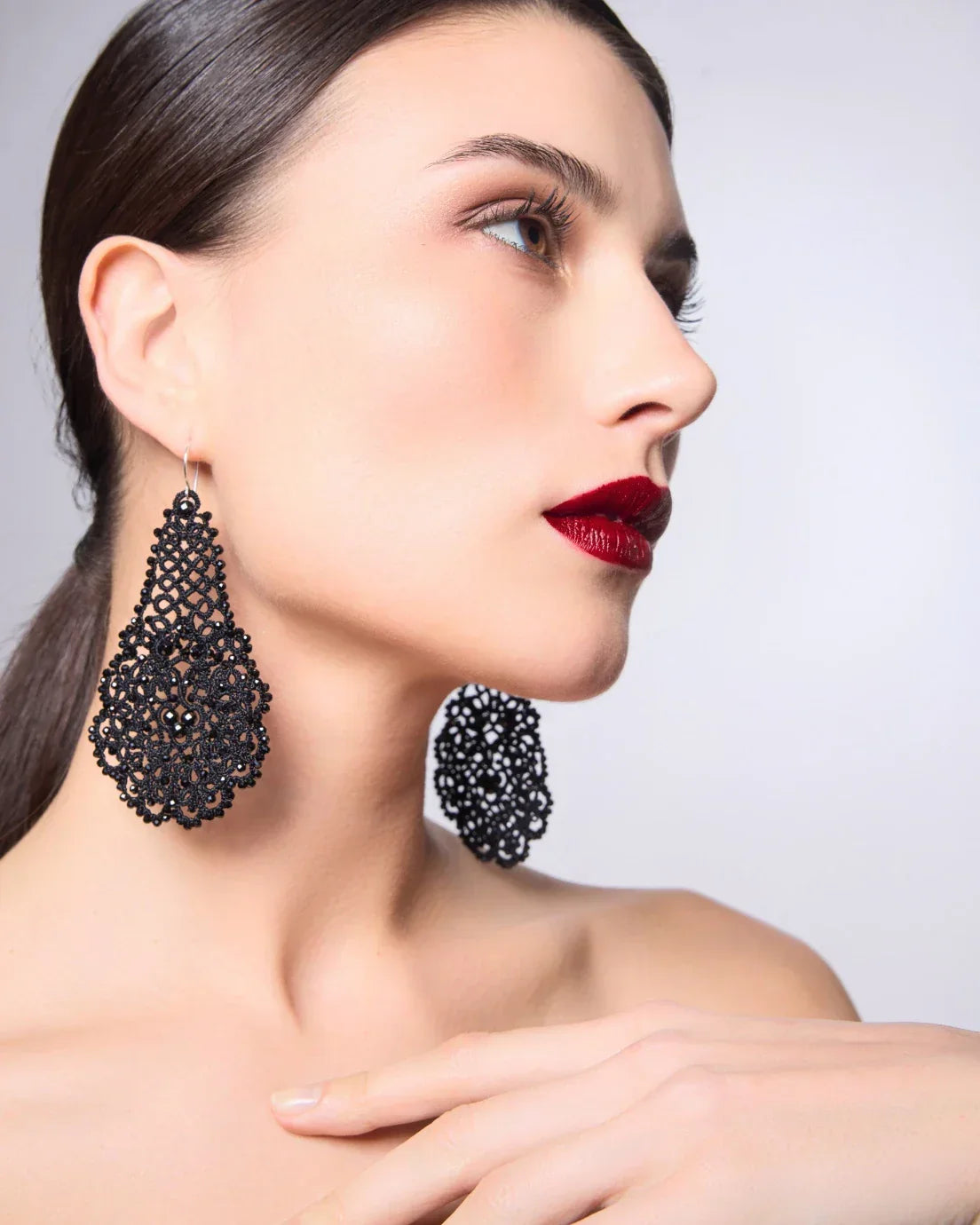 Black intricate lace Gerbera earrings, side view displaying detailed pattern and lightweight design on a model.