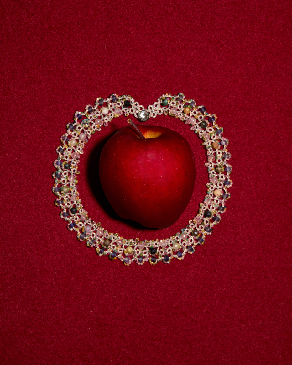 GRACE NECKLACE with multicolor gemstones, silk threads, mother of pearl button encircles a red apple on red backdrop
