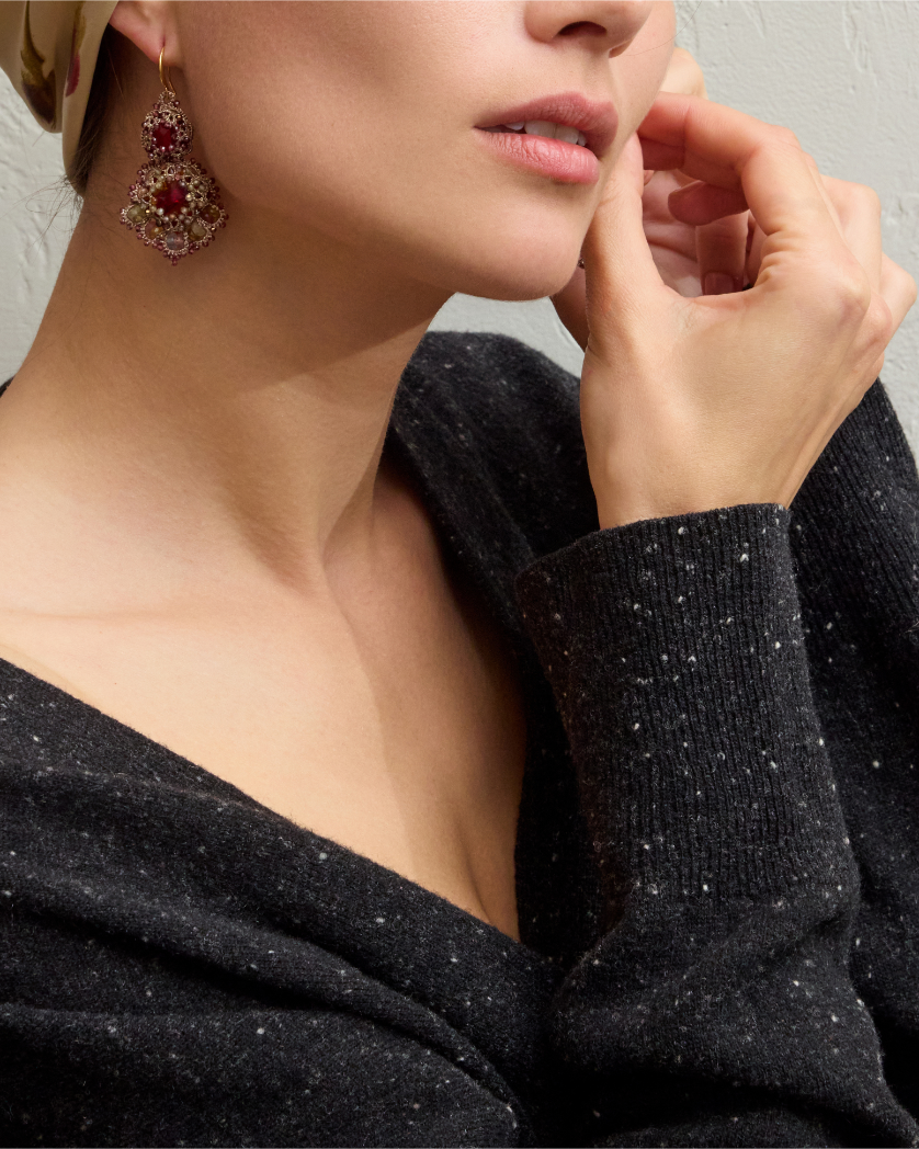 Red silk Kimberly earrings with intricate detailing, worn by a person, highlighted against a textured fabric background.