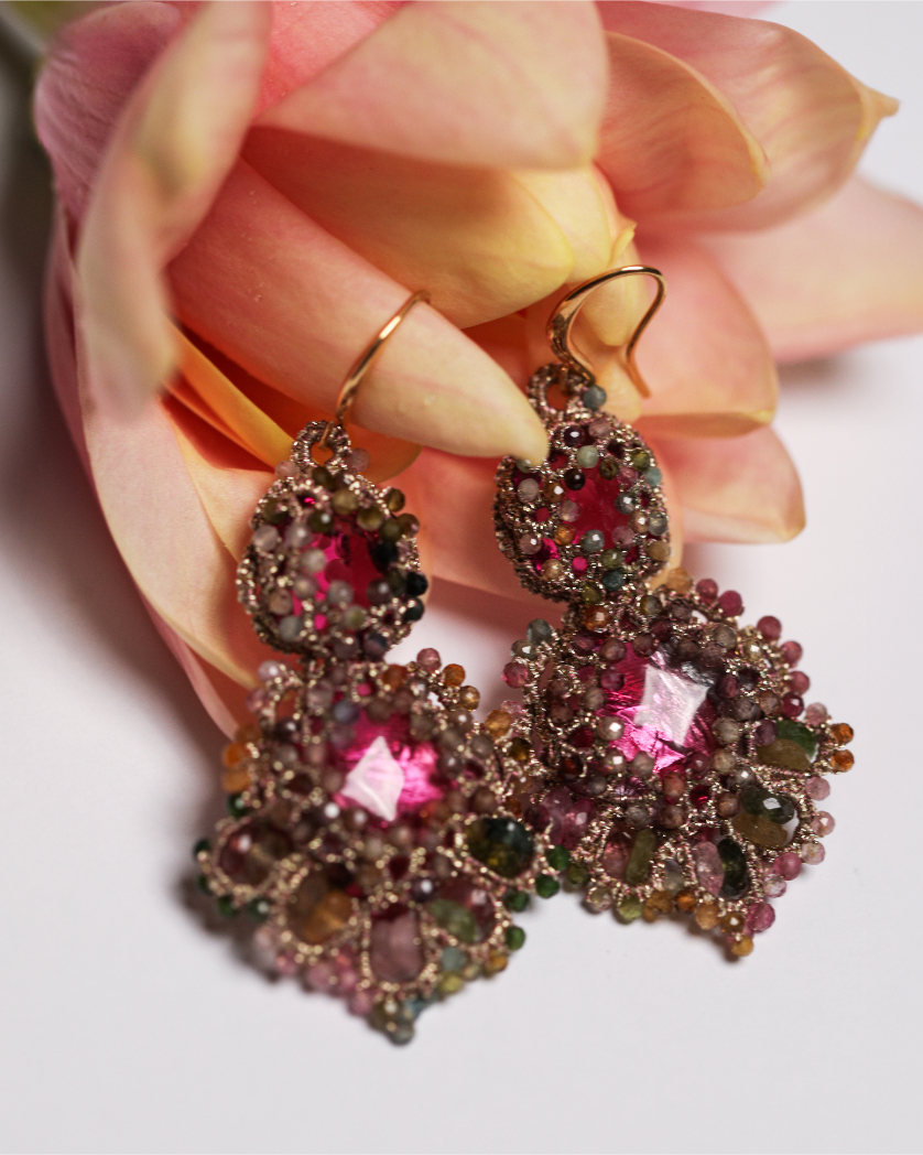 Rose silk earrings with intricate gemstone detailing against a soft floral background.