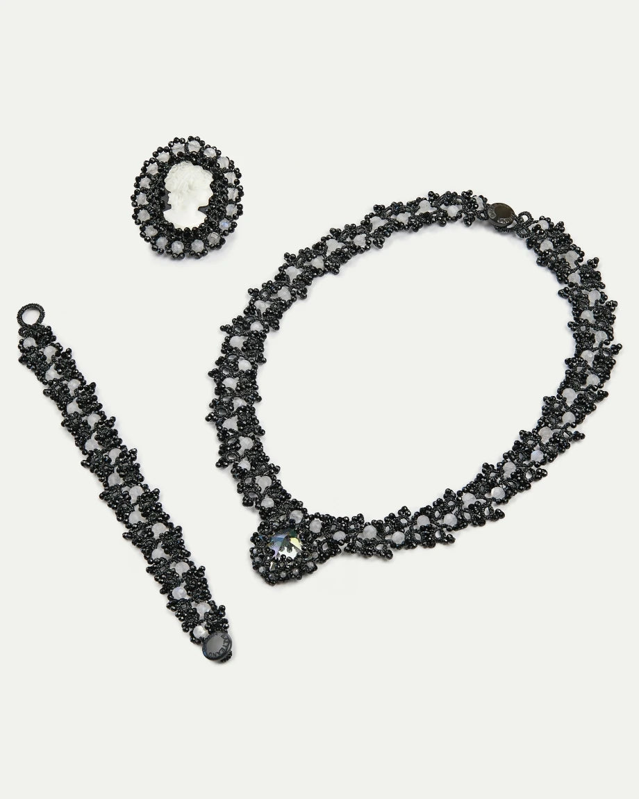 Black silk, silver, and glass detail with intricate textures on Margueritte brooch and jewelry set.