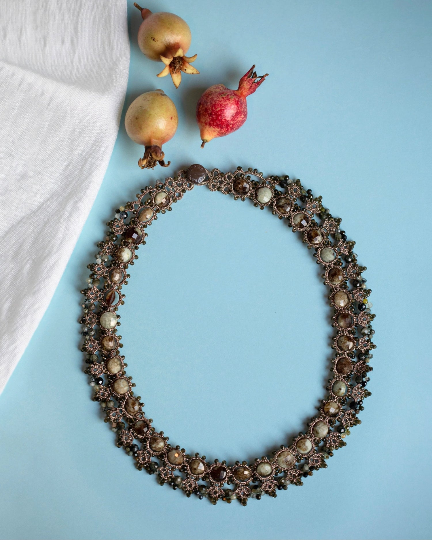 Gold Melody necklace with intricate silk and pearl detailing, featuring textured links and decorative accents.