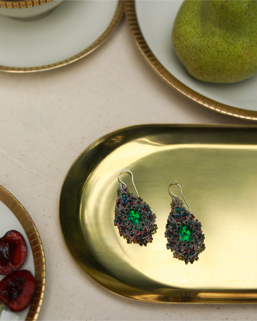Green silk earrings with pearl, crystal, sapphire, and emerald detailing on a gold tray.