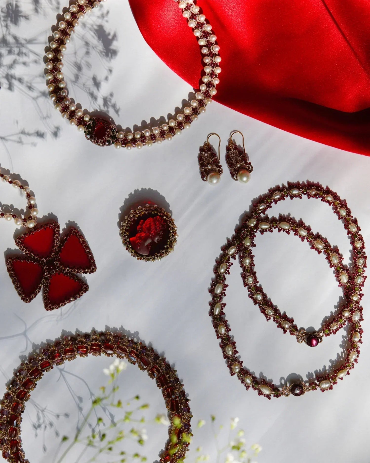 Red silk and pearl detail with sapphire accents on Penelope brooch, showcasing intricate craftsmanship.