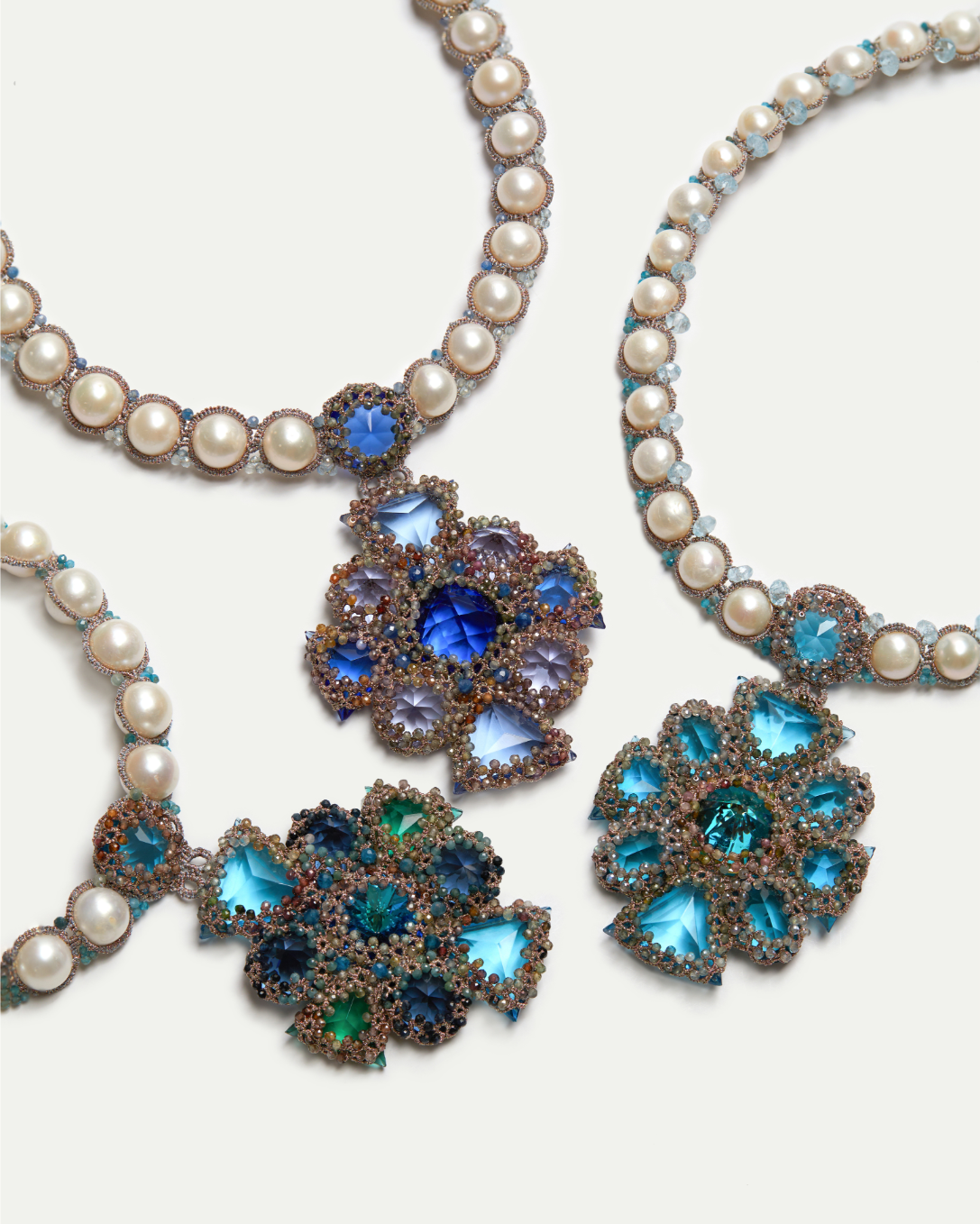 Pearl and gemstone necklaces with intricate blue and green floral patterns.