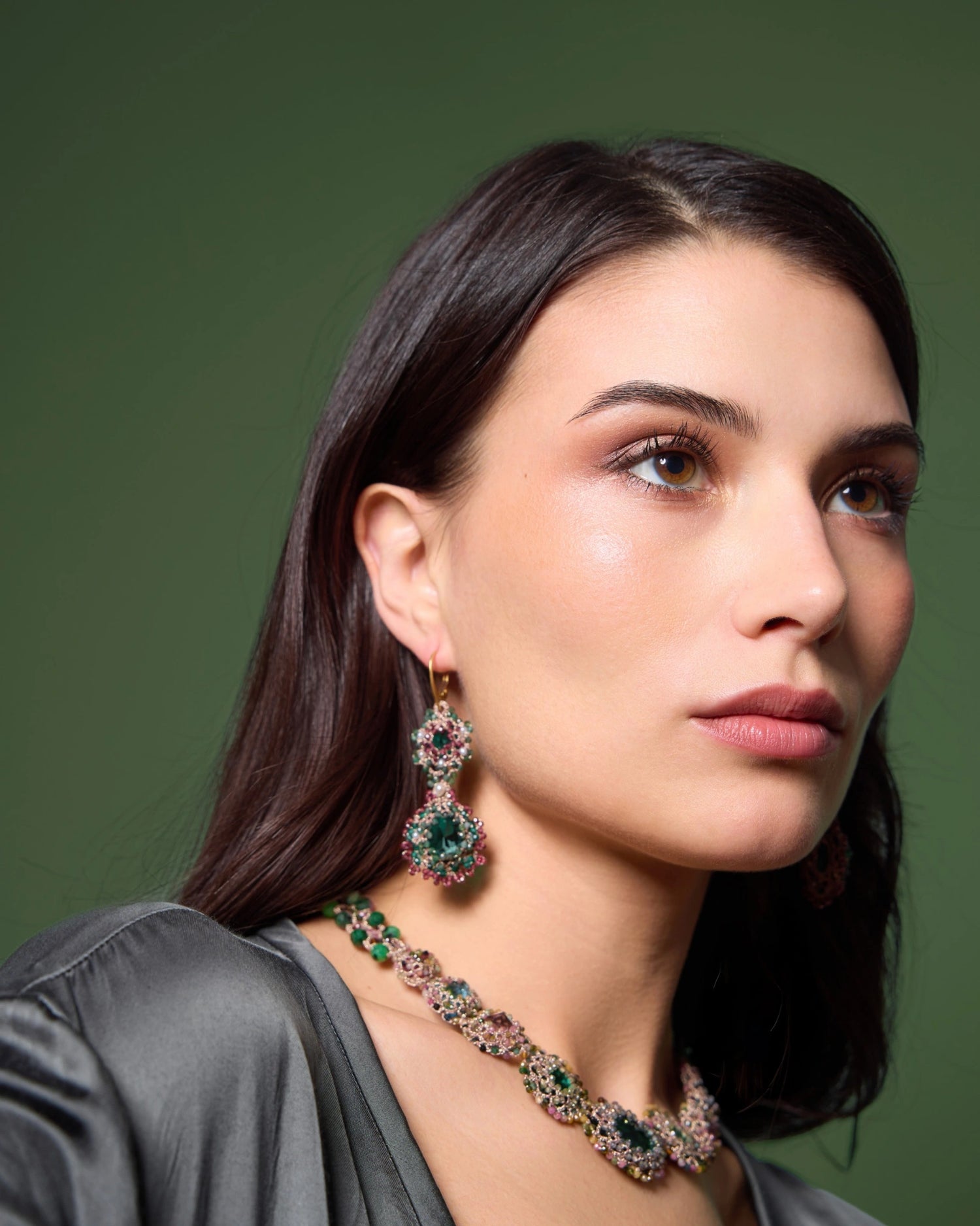 Yasmine earrings featuring green crystals, pearls, garnet gemstones, gold-plated silver hooks, set on a model.