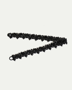 Black silk choker with intricate beaded pearl detailing and clasp, showcasing elegant texture and craftsmanship.