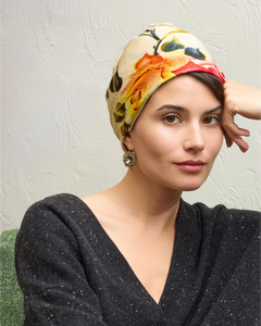 Silk multicolor headscarf with floral pattern complements gold and green intricate earrings.
