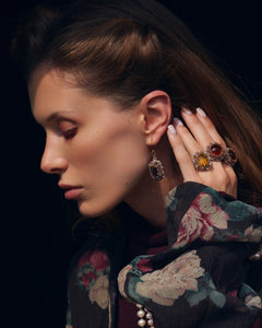 Rose Constance earrings with silk, gold, crystal details; intricate sapphire design against floral backdrop.