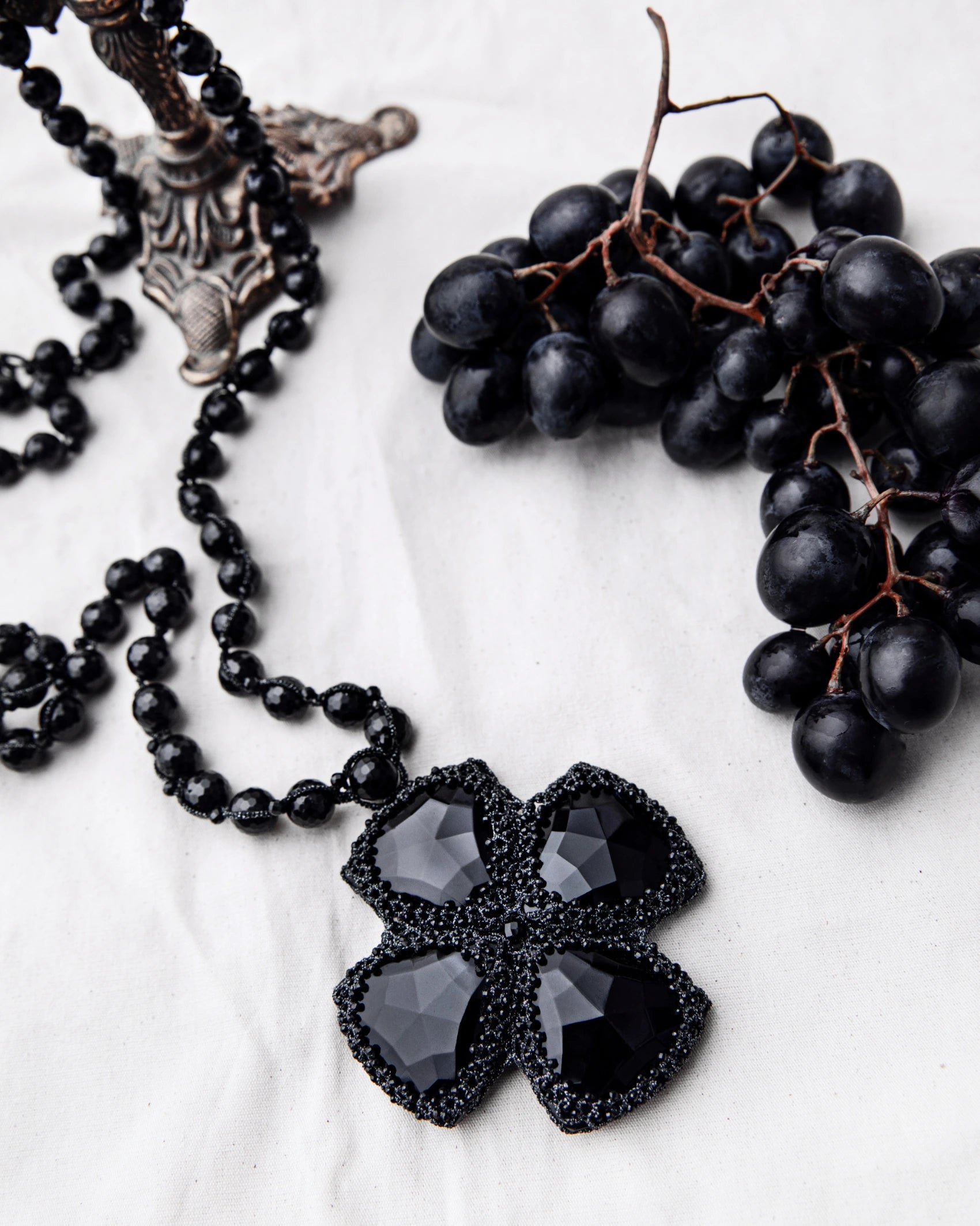 DITA Pendant with black vintage glass, spinel gemstones, silk and pearl detailing, on white background.