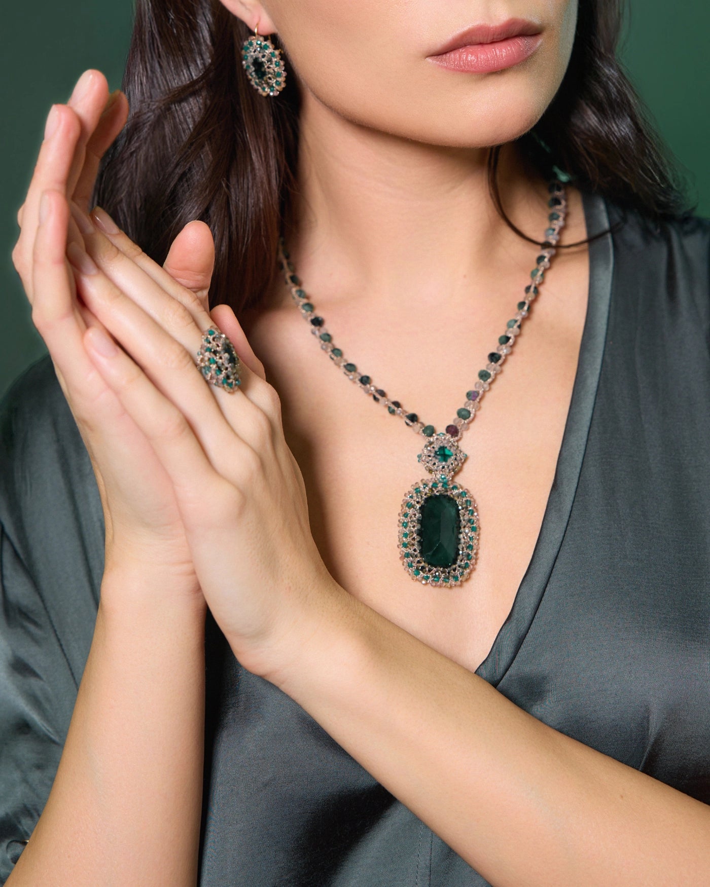 Green silk, gold, silver crystal earrings with emerald detail, showcasing intricate craftsmanship and refined texture.