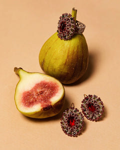 Red ECATERINA EARRINGS with gemstone center, surrounded by intricate crystal design, displayed on light surface.