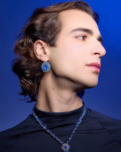 Blue gemstone ECATERINA EARRINGS in side view, featuring intricate detailing, worn by a person.