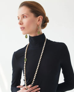 Elegant green Eloise earrings with gold, silver, crystals, and tourmaline detailing against a black top.