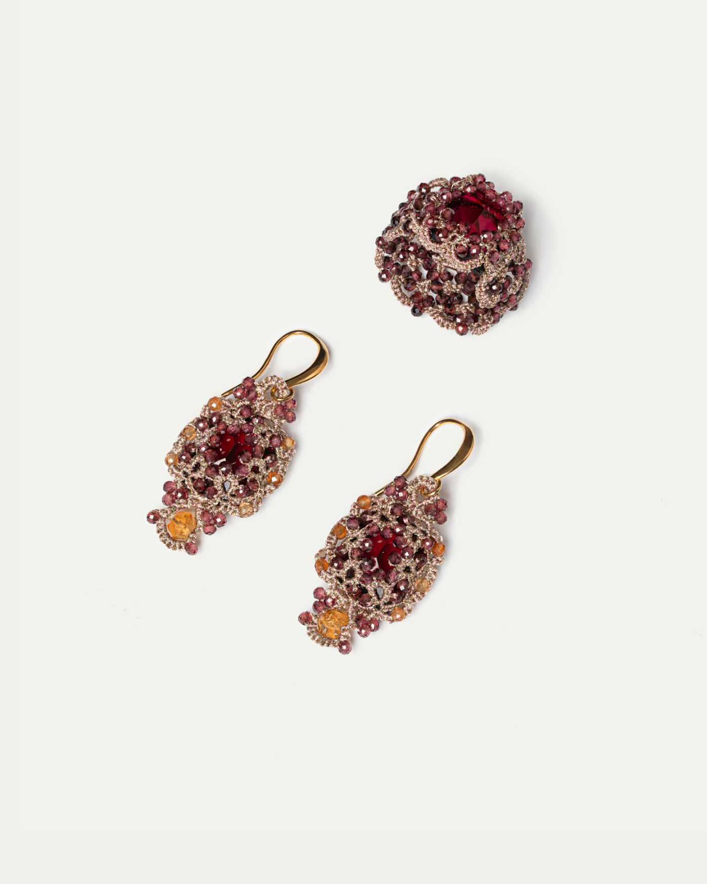 Gold and red jeweled earrings with intricate detailing next to a matching ring on a white background.