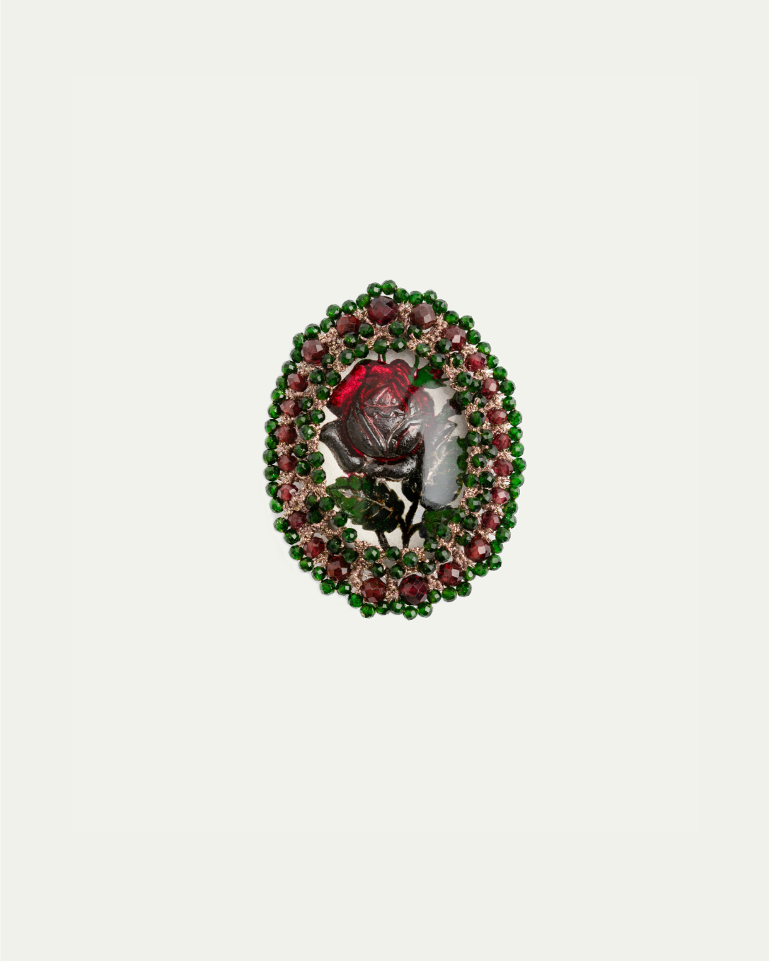 Oval brooch with red rose centerpiece, embellished with pink and green gemstones, featuring intricate detailing.