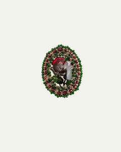 Oval brooch with red rose centerpiece, embellished with pink and green gemstones, featuring intricate detailing.