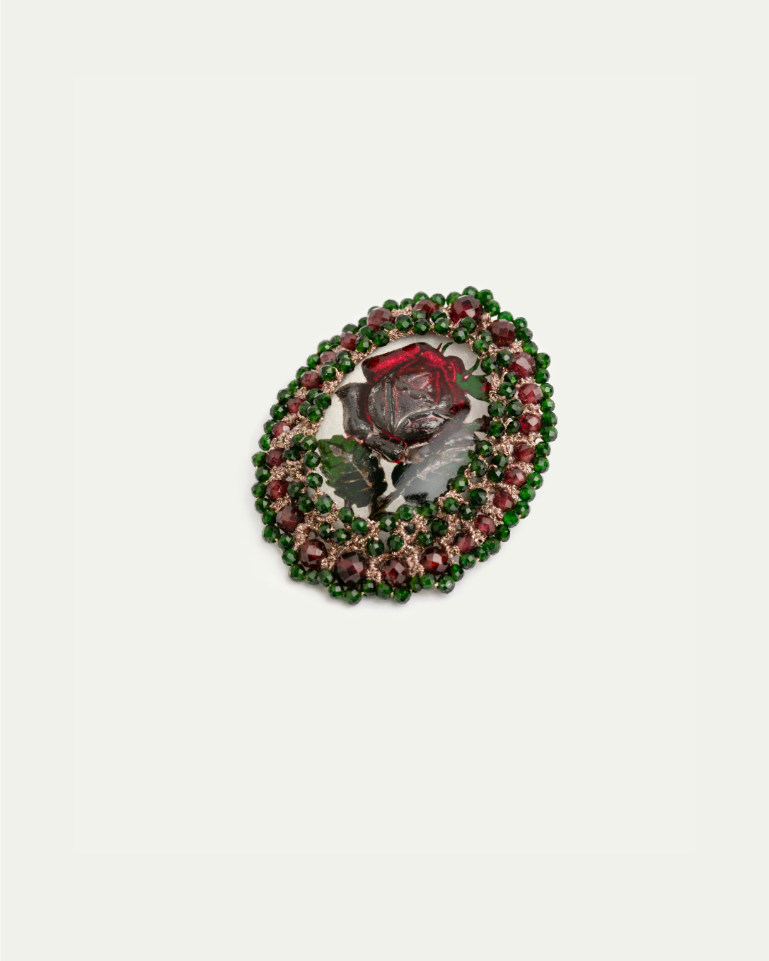 Silk brooch with detailed red and green floral design, surrounded by sparkling gemstones.