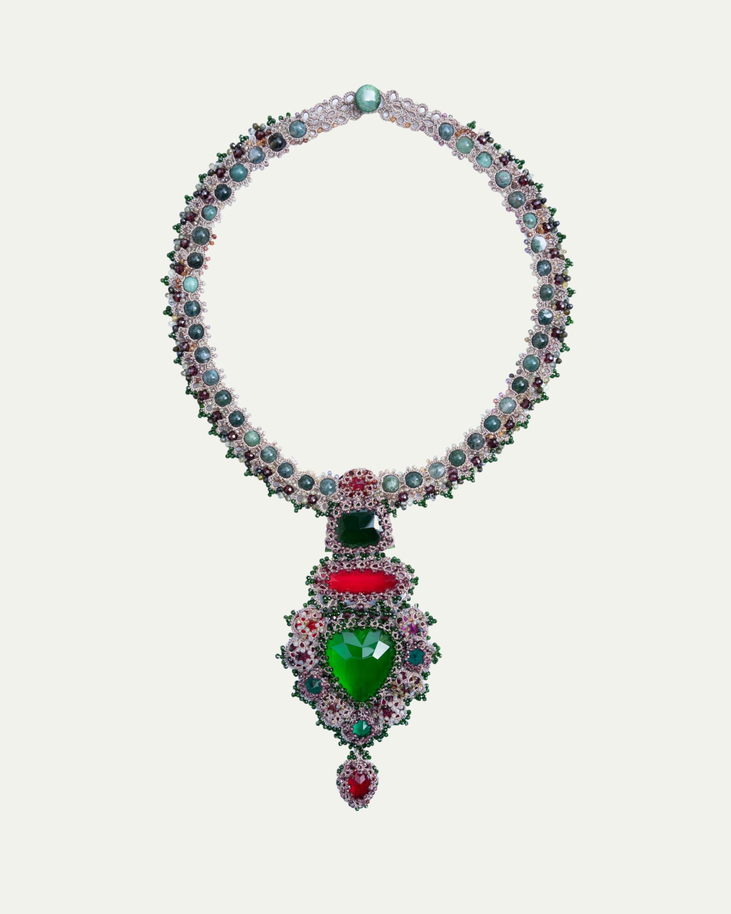Elegant necklace with emerald green and ruby red stones, intricate side view, adorned with pearls and silver detailing.