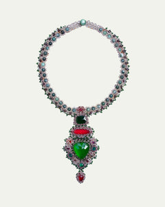 Elegant necklace with emerald green and ruby red stones, intricate side view, adorned with pearls and silver detailing.