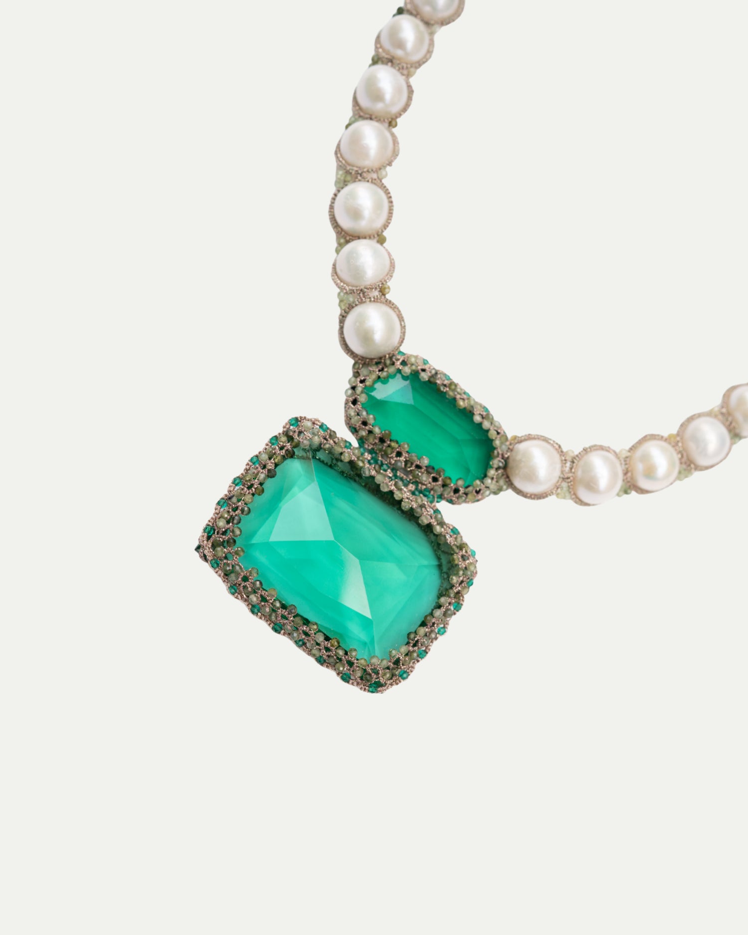 Necklace with green gemstones and pearl beads on a white background