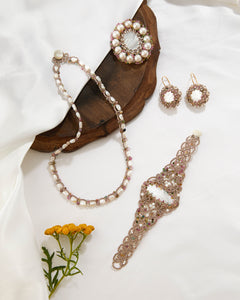 Silk bracelet with freshwater pearls and tourmaline in white, intricate lace-like detailing, displayed on fabric.