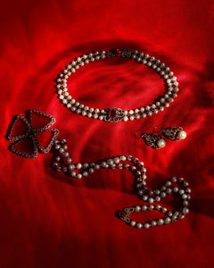 Red silk backdrop with freshwater pearl, garnet pendant details; garnet and pearl accentuated necklace and earrings.