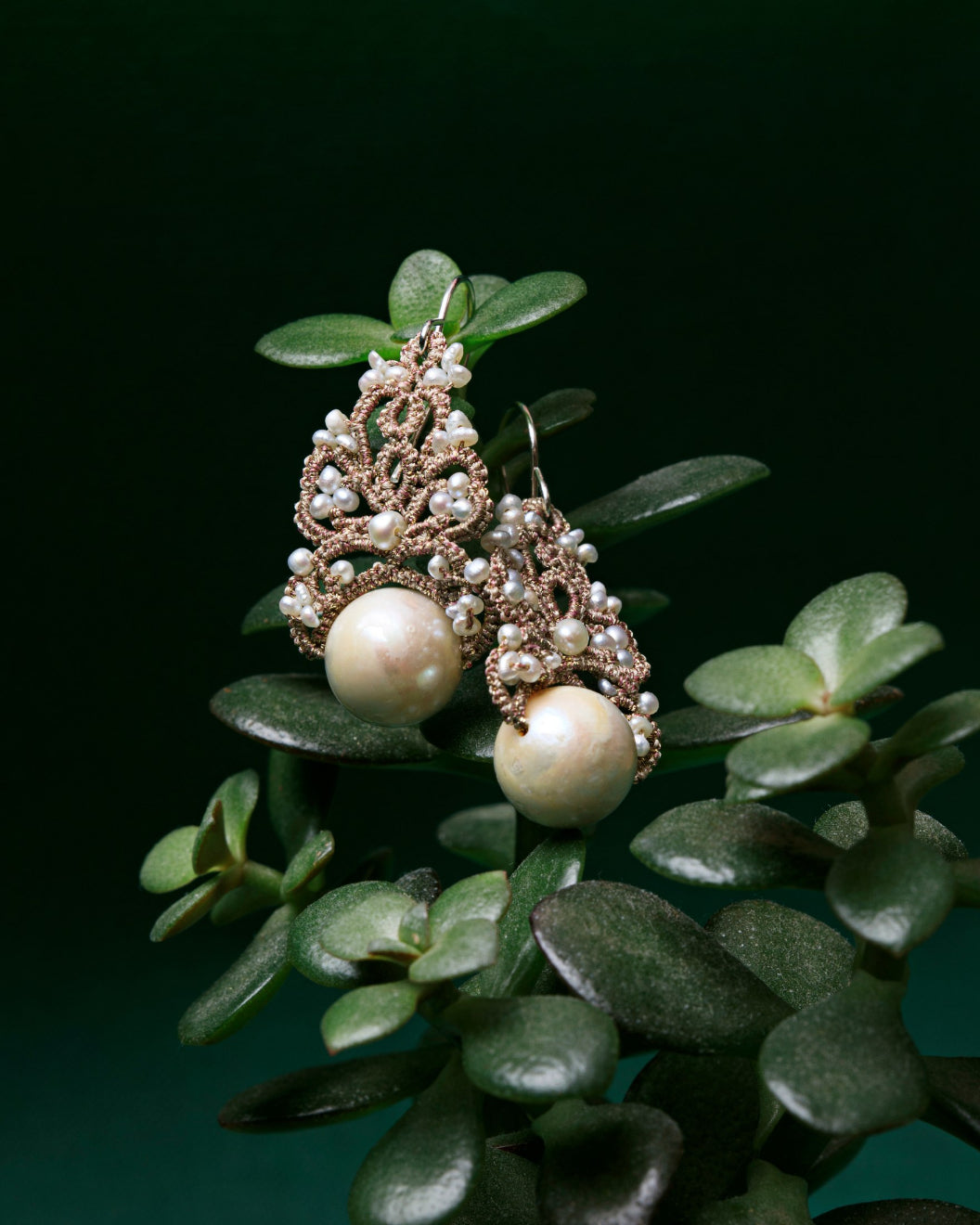 Gillet Earrings with freshwater pearls, silk, silver hooks on green foliage.