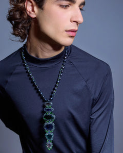 Black pearl necklace with glass details and freshwater pearls, worn over a dark top, highlighting intricate textures.