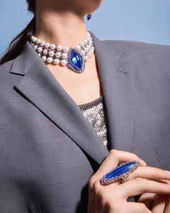 Blue pearl choker with large Kyanite gemstone and silk detailing worn with a grey suit.