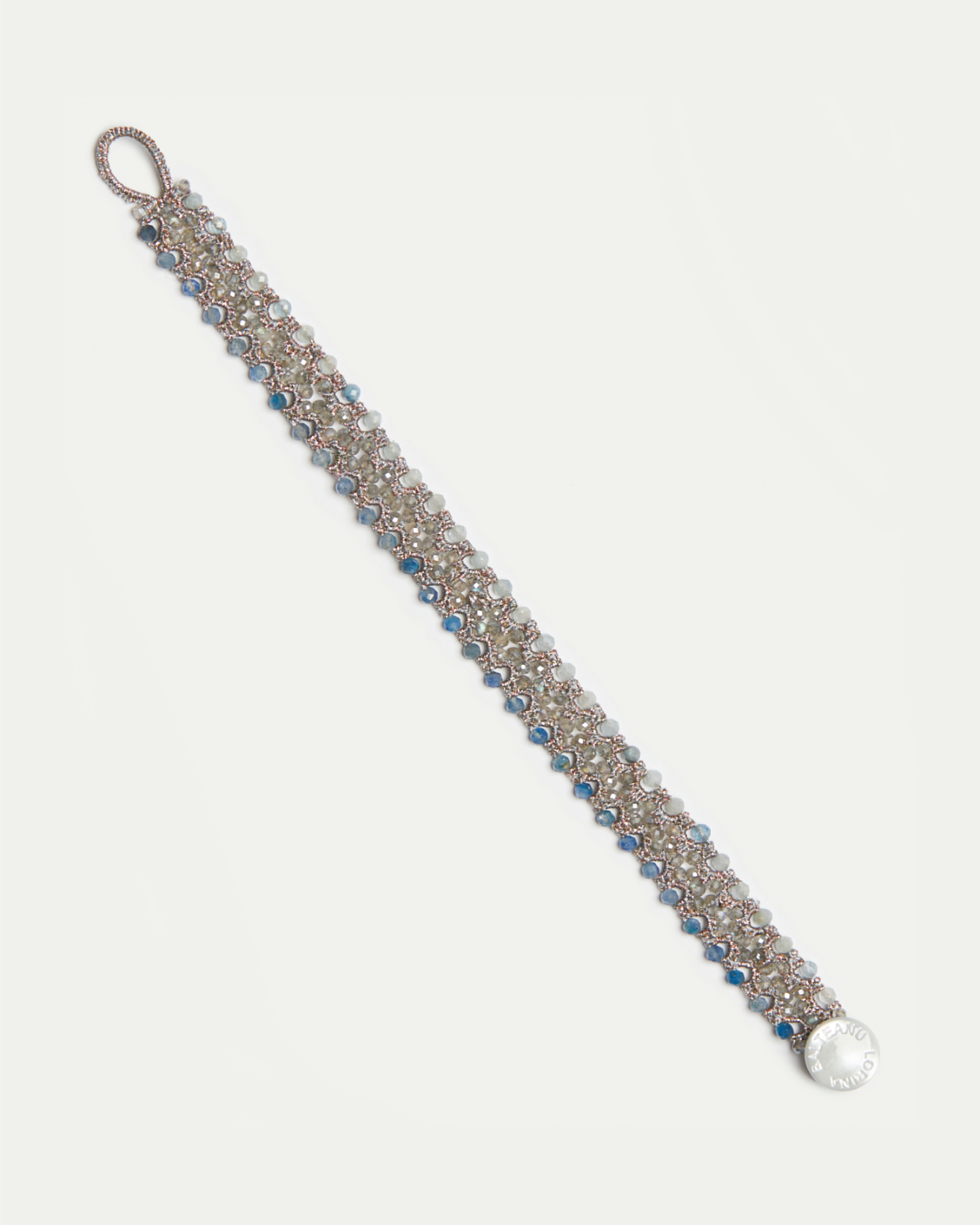 Blue Linda bracelet with intricate silver links, blue and white beads, clasp, and circular engraved charm.