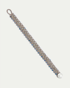 Blue Linda bracelet with intricate silver links, blue and white beads, clasp, and circular engraved charm.