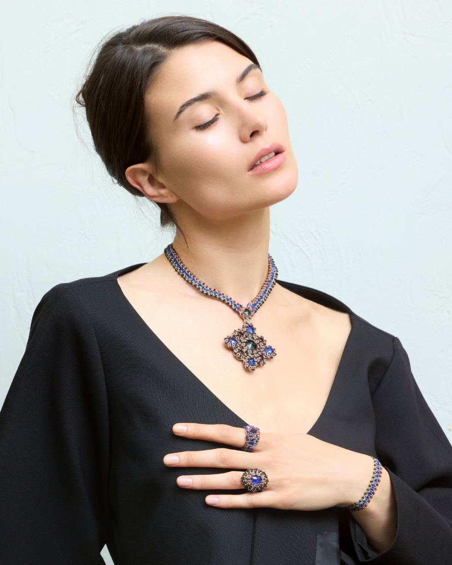 LINDA RING with multicolor crystals, garnet, tanzanite gemstones, silk, and metallized thread, worn on hand.