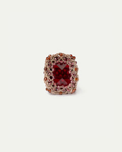 Red garnet ring with intricate silk and crystal detailing.