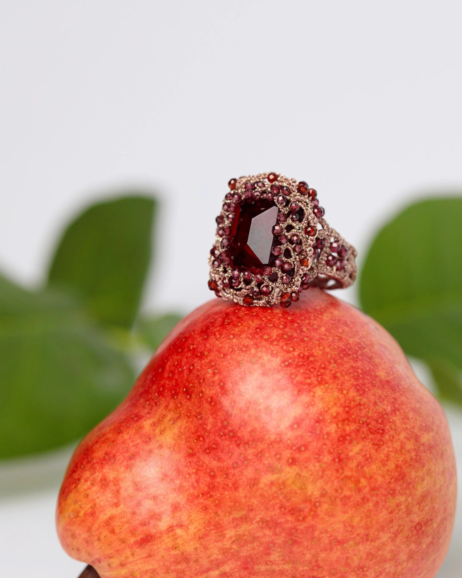Garnet and crystal ring with silk detailing, red color, featuring intricate gemstone settings.