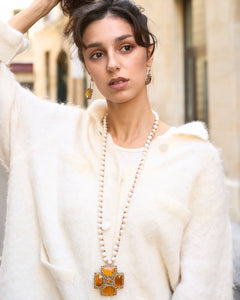 Gold Malta Pendant with pearl chain, featuring silk and freshwater pearls, worn against a soft cream sweater.