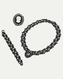 Black silk, silver, and glass detail with intricate textures on Margueritte brooch and jewelry set.