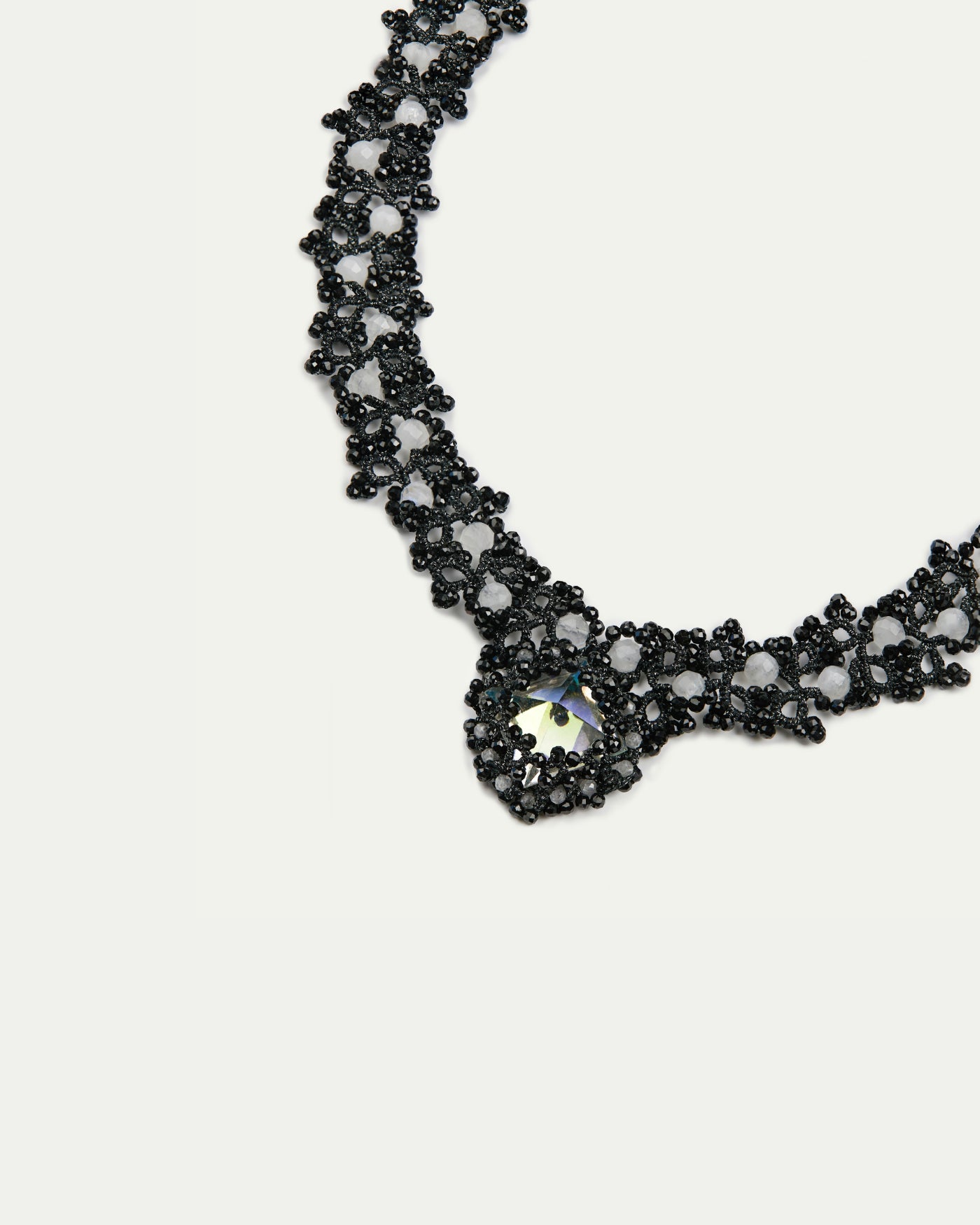 Black beaded Margueritte necklace, intricate lattice pattern with reflective central gem, elegant side view.