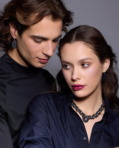 Black silk, pearl, and crystal Margueritte necklace detailed texture on dark fabric background.