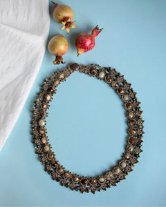 Gold Melody necklace with intricate silk and pearl detailing, featuring textured links and decorative accents.