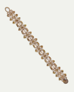 Gold PAIGE bracelet with silk, freshwater pearls, garnet, intricate detailing, and luxurious texture.