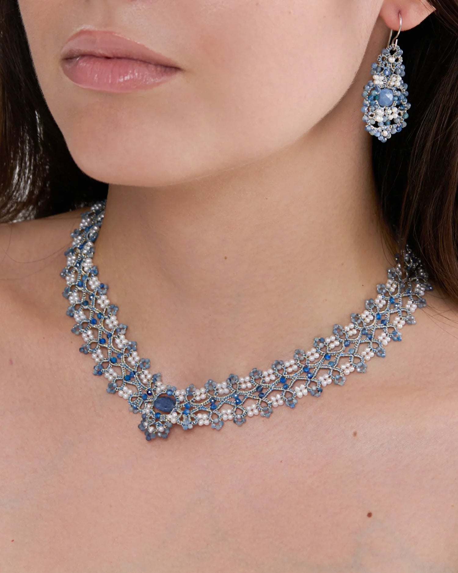 Elegant blue beaded necklace with intricate design on model's neck, matching beaded earring visible.