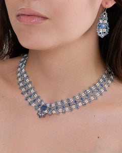 Elegant blue beaded necklace with intricate design on model's neck, matching beaded earring visible.