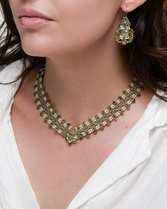 Green PAIGE necklace with silk, freshwater pearls, and tourmaline detailing, worn by a person in white shirt.