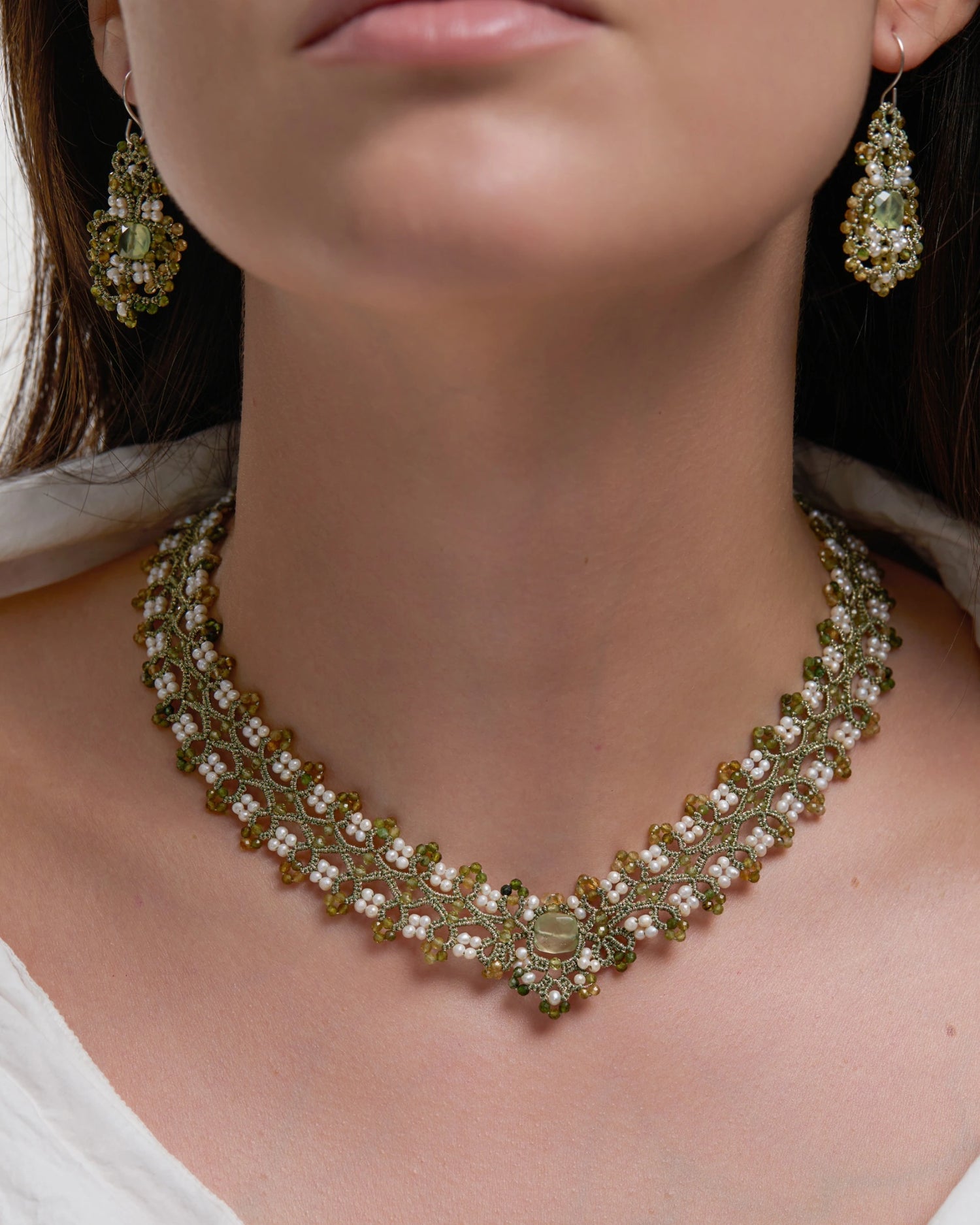 Green silk and freshwater pearl necklace featuring tourmaline details on a woman's neck.
